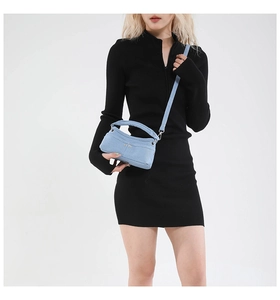 Dettaglio mini borsa in denim azzurro con tracolla larga e borchie metalliche