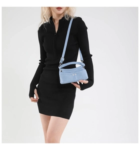 Detail of light blue denim handbag with front pockets and adjustable shoulder strap