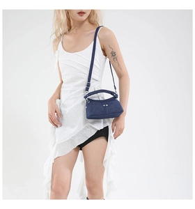 Blue washed denim crossbody bag featuring silver metal rivets and adjustable shoulder strap