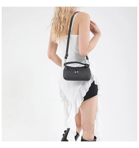 Dettaglio di una piccola borsa a tracolla in denim nero con fibbie metalliche