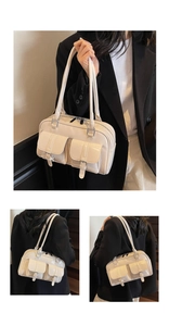 Detailed view of beige shoulder bag featuring dual front pockets and silver metal buckles