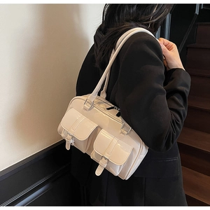Detailed side view of glossy cream faux leather tote bag with functional buckled pockets