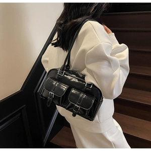 Glossy black patent leather tote bag with dual front pockets on wooden stairs