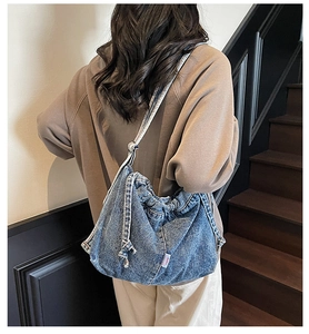 Vue arrière d'un mannequin portant le sac hobo en denim bleu avec plis et cordon de serrage