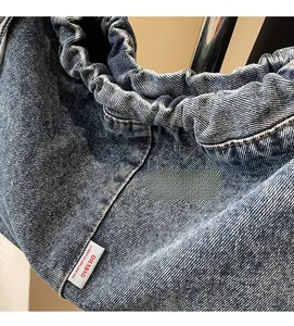 Détail du sac cabas en jean bleu avec fermeture plissée élastique et étiquette OXLBAG