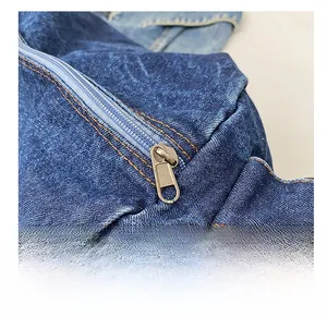 Macro shot of smooth bronze metal zipper and contrast stitching on dark blue denim bag