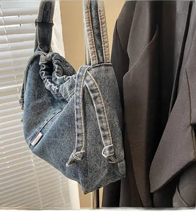 Détail d'un cabas en denim bleu avec fermeture à cordon et étiquette de marque