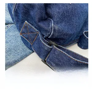 Macro shot of precise yellow stitching and adjustable buckle on blue denim tote bag