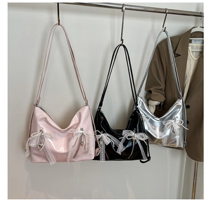 Detailed shot of three patent leather tote bags with lace trim and pearl bow pendants