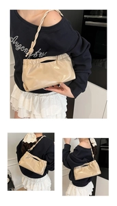 Close-up of beige ruched dumpling bag with woven strap and glossy faux leather texture