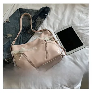 Close-up of light pink tote bag with lace bow, pearl charm, and double zipper details