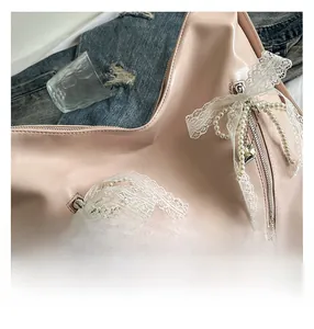 Close-up of pink PU leather tote with lace bows, pearl chains and silver heart charm