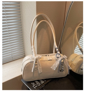 Detail of cream underarm bag with lace bow, checkered ribbon and cute bear charm