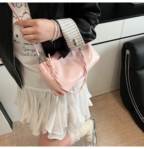 Pink glossy faux leather shoulder bag with a unique woven knotted handle shown on model