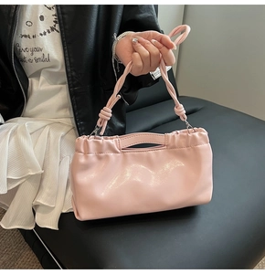 Detail of pink glossy PU drawstring handbag with elegant knot handle and pleated texture