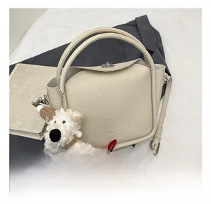 Détail du sac en cuir grainé blanc cassé avec fermoir en métal et breloque ourson