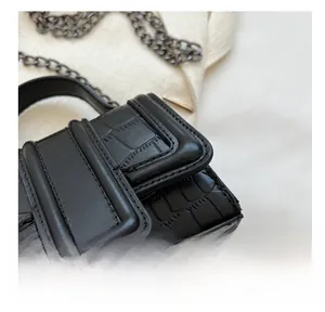 Close-up of black crocodile pattern leather with fine stitching and gunmetal chain detail