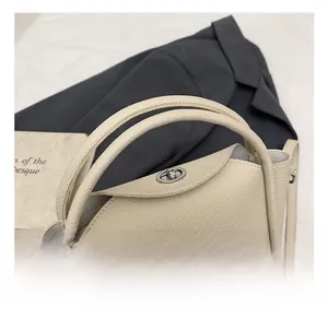 Détail du sac à main en cuir crème grainé avec fermoir rotatif argenté et poignée souple