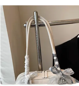 Detail of ivory shoulder bag handle with lace ribbons and black-white checkered bow
