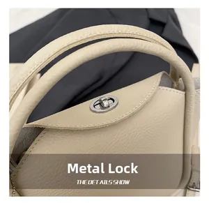Gros plan d'un sac à main beige en cuir grainé avec un fermoir pivotant en métal doré