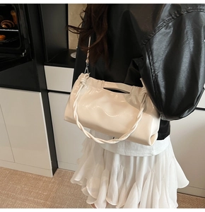 Detail view of a cream white glossy patent leather shoulder bag with twisted rope handle
