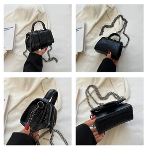 Detail view of mini black handbag with crocodile pattern texture and metallic chain