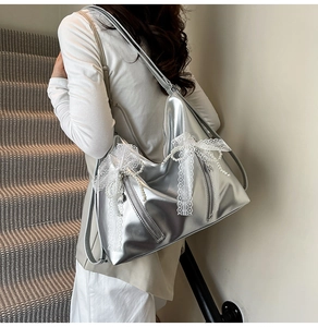 Detail of silver metallic tote bag with white lace bows and decorative pearl chain