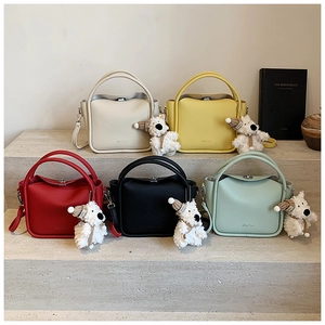 Détail de mini sacs bandoulière en cinq couleurs avec breloques chien et fermoirs en métal