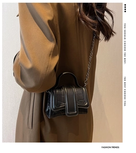 Détail d'un mini sac carré gaufré croco avec chaîne argentée porté par un modèle