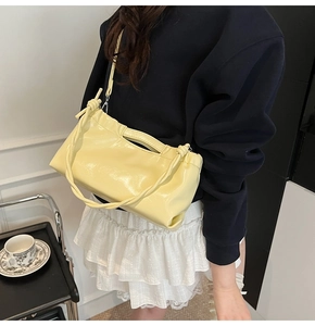 Close-up of glossy yellow PU leather handbag with drawstring detail and knotted handle strap