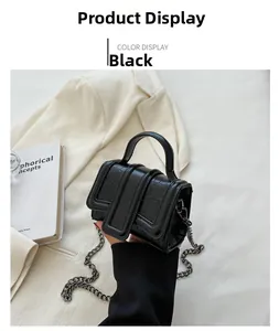 Detail of a mini black crossbody bag with crocodile texture and metal chain strap