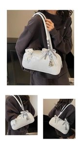 Detail of light blue cylinder bag with white lace bow and silver heart charm