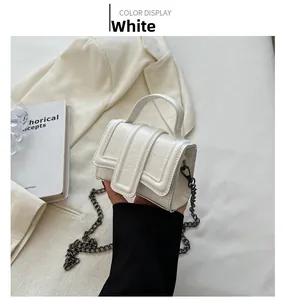 Detail of white crocodile pattern mini bag with dark gunmetal chain strap and top handle