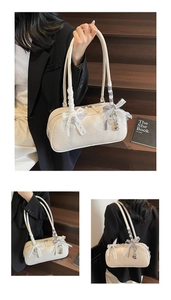 Detail of cream white faux leather underarm bag with lace bow and cute metal pendants