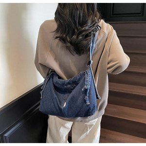 Détail du sac fourre-tout en denim délavé bleu marine avec cordon de serrage et bandoulière