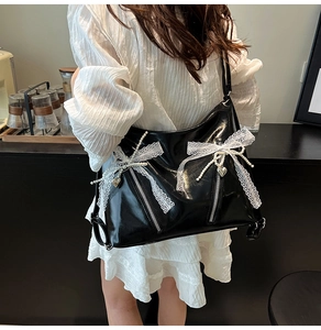 Detail of black patent leather tote bag with white lace bows and pearl decorations