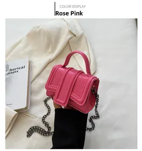 Close-up of rose pink mini handbag with crocodile texture and metallic chain strap