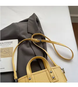 Detail of yellow bucket bag with lychee texture leather and silver rivet accents