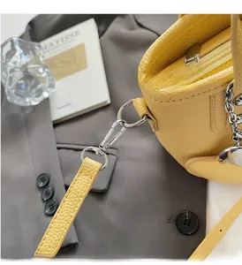 Detailed close-up of bright yellow lychee pattern leather bucket bag with silver hardware