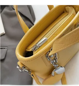 Close-up of a smooth silver zipper and lychee grain leather on a yellow bucket bag