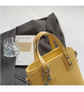 Detail of yellow lychee grain leather bucket bag with silver studs and chain trim