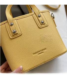 Detail of yellow lychee grain leather bucket bag with silver studs and brand embossing