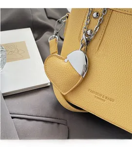 Detail of yellow lychee leather bucket bag with silver chain and heart charm