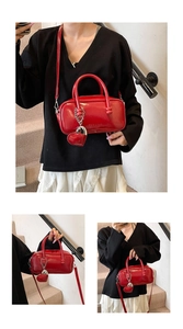 Detail of red glossy bowling bag featuring heart charm and embossed brand logo