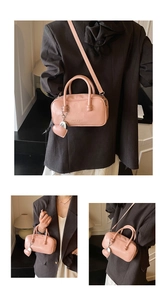 Detailed view of light pink leather bowling bag with heart charm and brand embossing