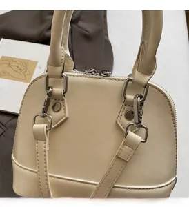 Detail of silver metal hardware and fine stitching on a cream leather shell handbag
