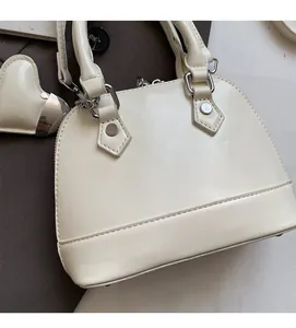 Detail of cream shell handbag with heart charm and silver metal hardware accents