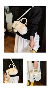 Detail of white vintage Boston bag with glossy finish and heart chain charm