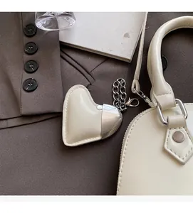 Close-up of cream leather heart charm with silver hardware on a luxury handbag