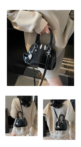 Detail of glossy black shell bag with silver hardware and heart-shaped leather charm